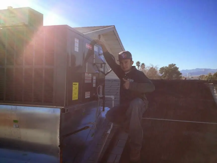 HVAC technician performing AC Tune-Up on a rooftop unit in Irvington